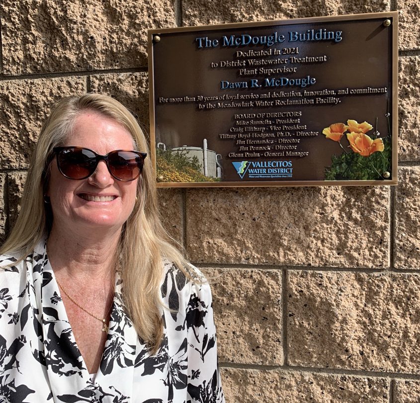 Dawn McDougle poses next to the plaque naming the administration building at the Meadowlark Reclamation Facility in her honor. Photo: Vallecitos Water DIstrict Dawn McDougle honored