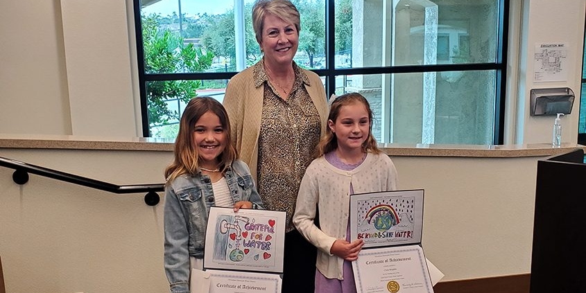 Poster contest winning artists Aria Drelich and Maia McAllum with OMWD Board President Christy Guerin. Photo: Olivenhain Municipal Water District