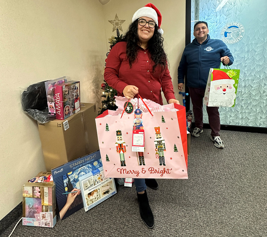Sweetwater Authority employees Gloria Achutegui, Records Management Specialist, and Michael Garcia, Assistant Board Secretary, display employee donations for the Authority's annual holiday giving effort. Photo: Sweetwater Authority