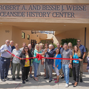 Tom Weese, son of Robert and Bessie Weese and historian Kristie Hawthorne perform the ribbon cutting at the new location of the Weese Oceanside History Center with members of the Oceanside Historical Society. Photo: Zach Cordner/The Osider.