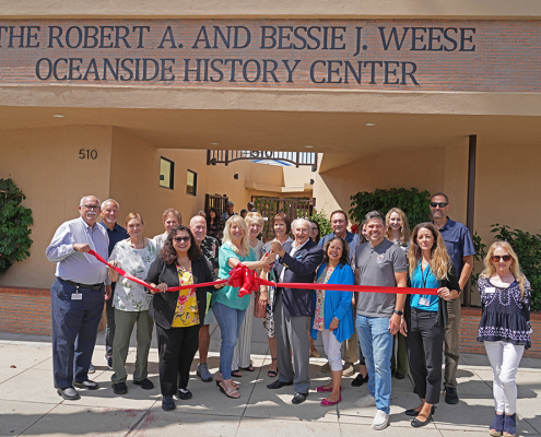 Tom Weese, son of Robert and Bessie Weese and historian Kristie Hawthorne perform the ribbon cutting at the new location of the Weese Oceanside History Center with members of the Oceanside Historical Society. Photo: Zach Cordner/The Osider.